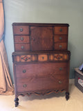 Full view of two-piece walnut chest on chest, showing upper cabinet with center door and side drawers, lower section with large drawers, turned feet, casters