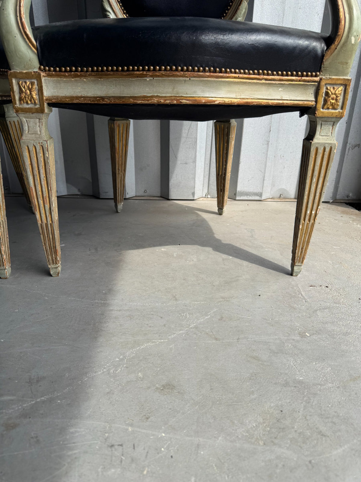 Chair base and legs detail showing fluted carved legs with gold leaf decoration and stretchers connecting the frame