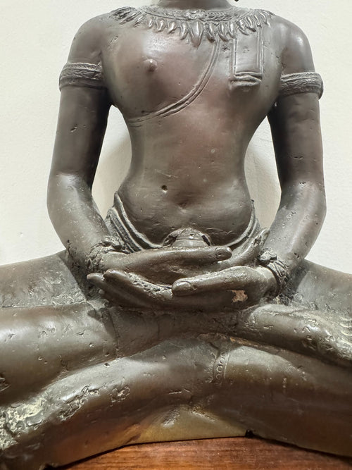 Close-up detail of Buddha torso showing draped robe, decorative chest ornaments, and arm positioning