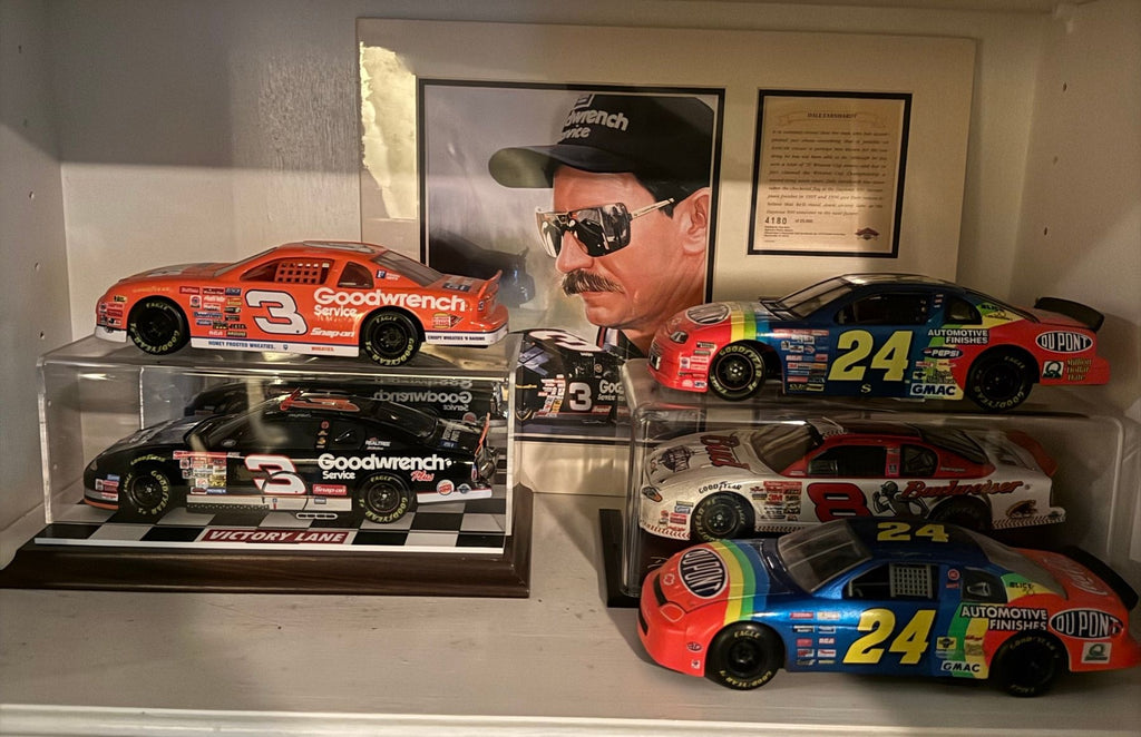 Two Earnhardt #3 and two Gordon #24 die-cast cars, a Budweiser #8 car and a framed Earnhardt print on a white shelf