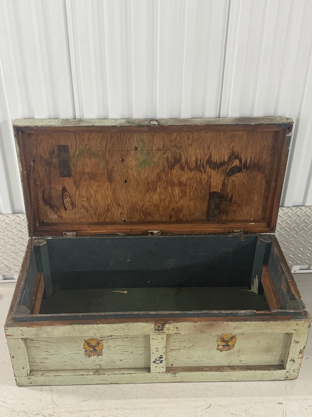 Interior view of open trunk showing dark wood-paneled lid and green canvas-lined base with metal reinforcements