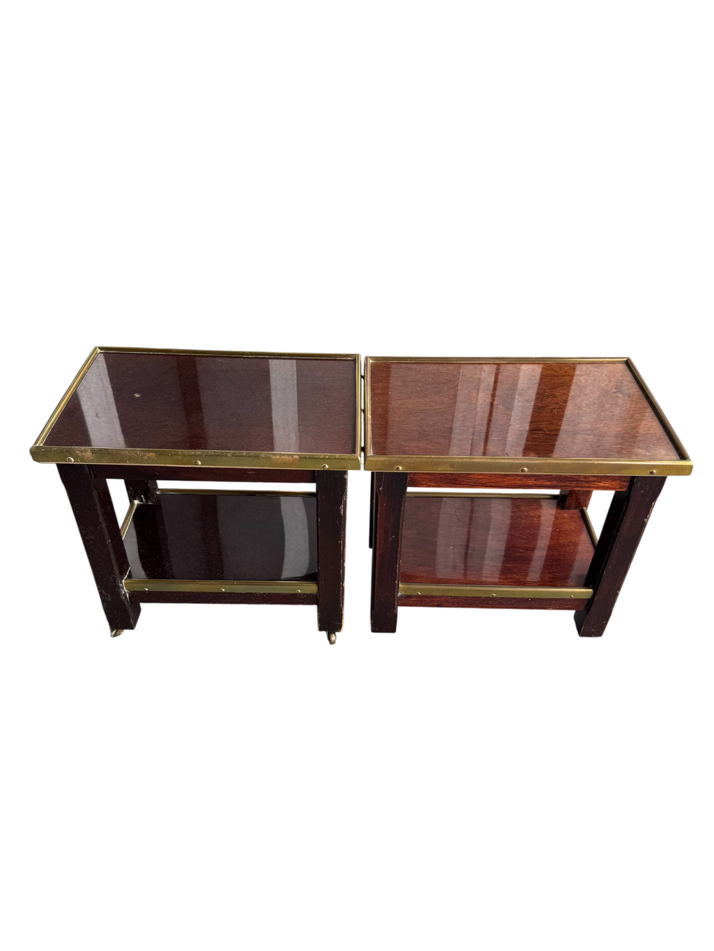 Pair of mahogany two-tier side tables with brass trim and casters, viewed from front