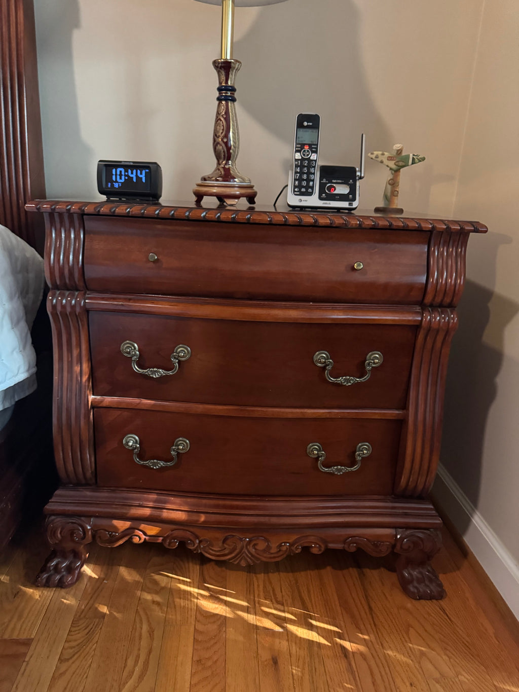 Second matching cherry-finish nightstand with the same carved detailing and claw feet, shown with the same tabletop items