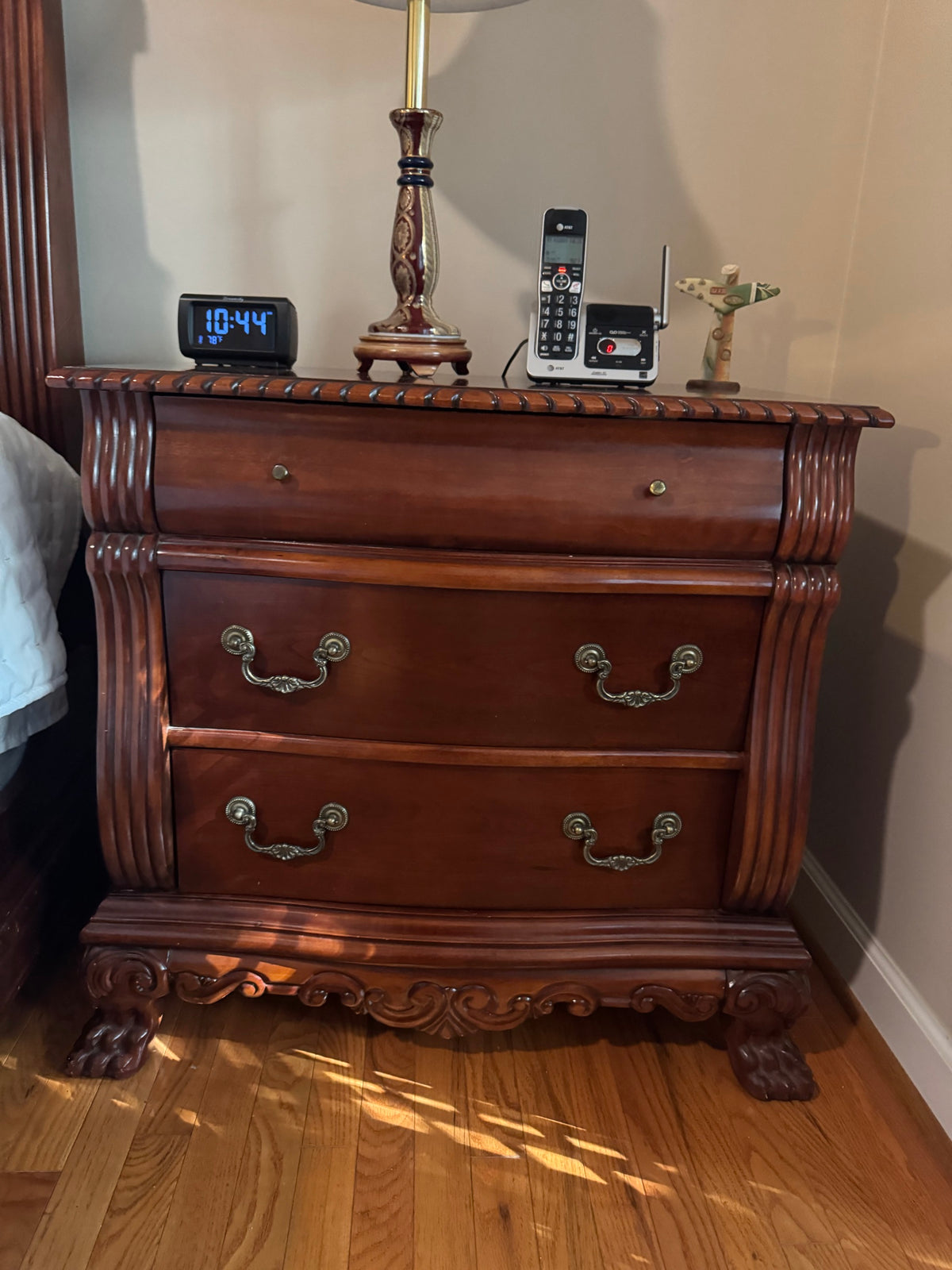Second matching cherry-finish nightstand with the same carved detailing and claw feet, shown with the same tabletop items