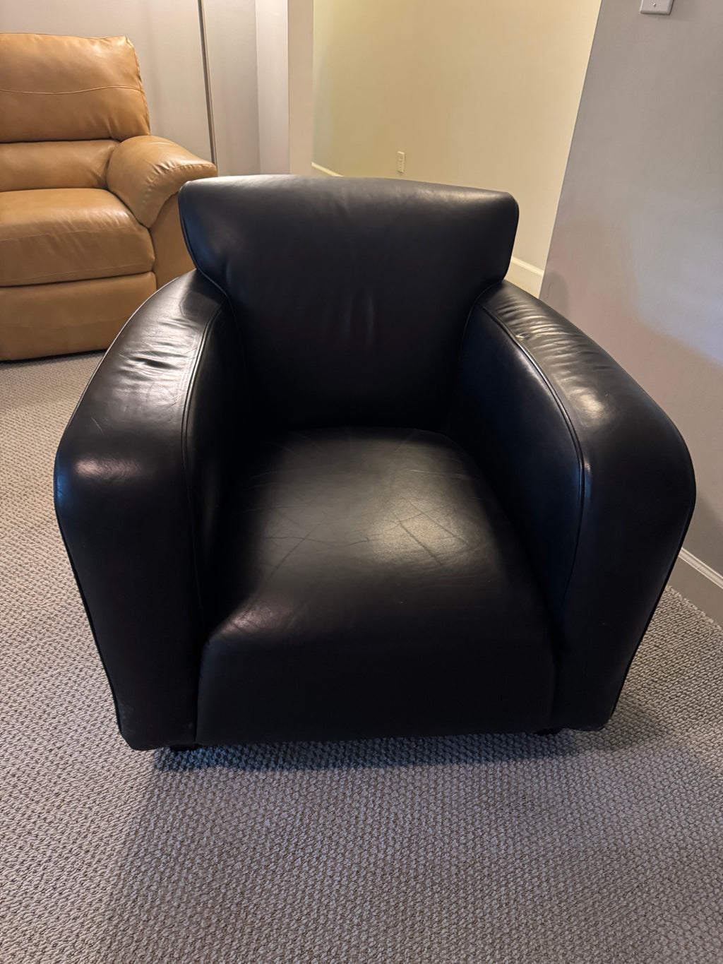 Black leather barrel chair viewed from the front showing seat and arms