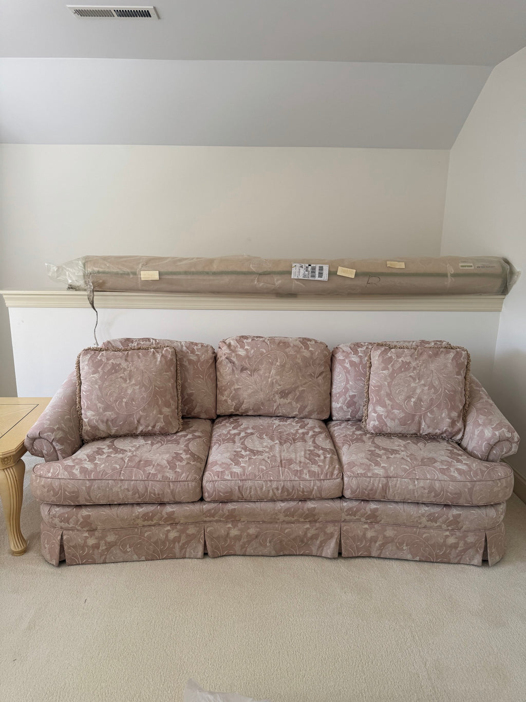 Mauve floral damask three-cushion sofa with rolled arms and skirted base, front view in room setting