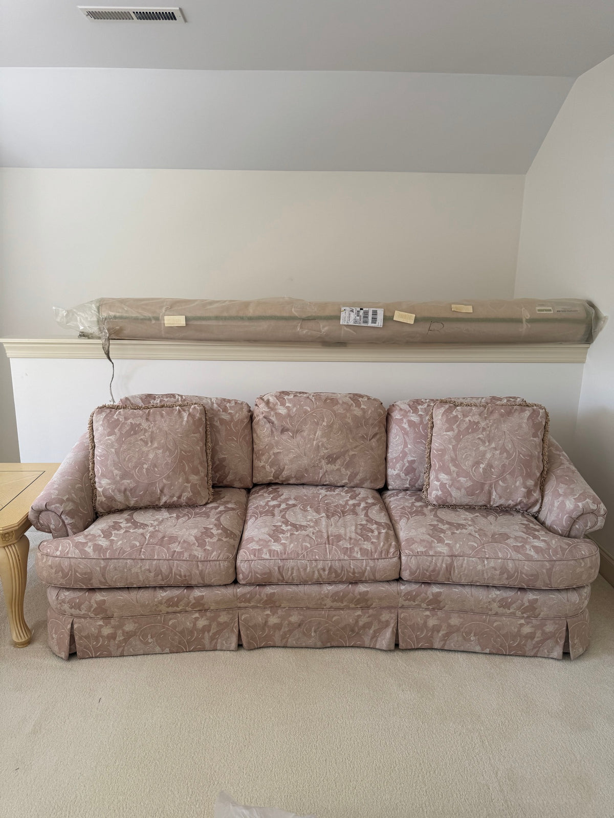 Mauve floral damask three-cushion sofa with rolled arms and skirted base, front view in room setting