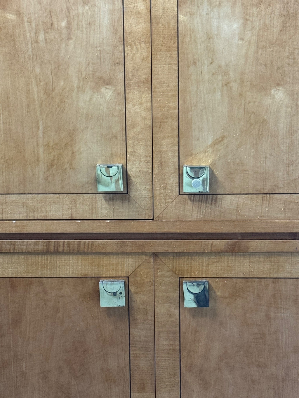 Close-up of brass hardware handles on upper and lower cabinet door pairs