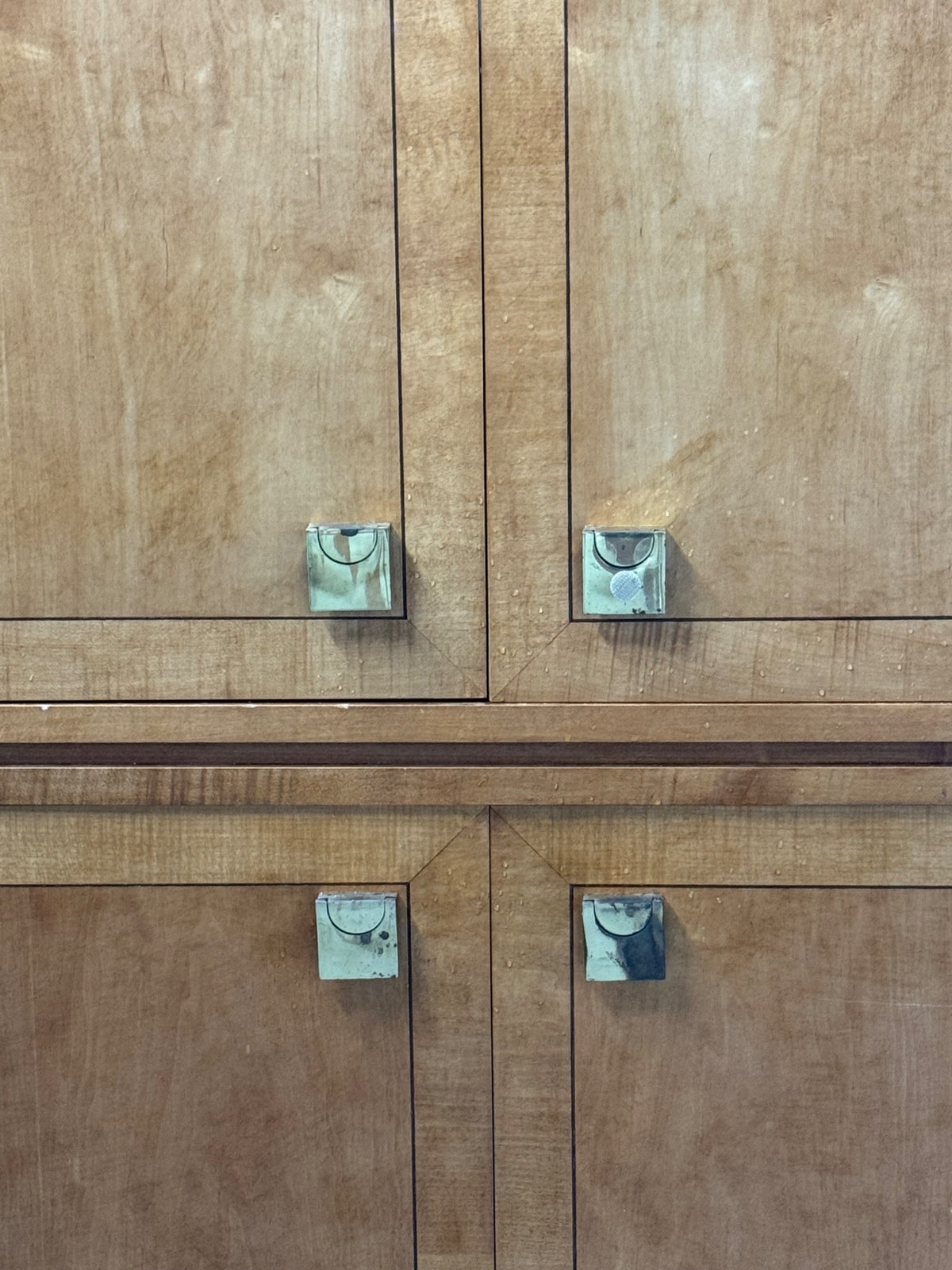 Close-up of brass hardware handles on upper and lower cabinet door pairs