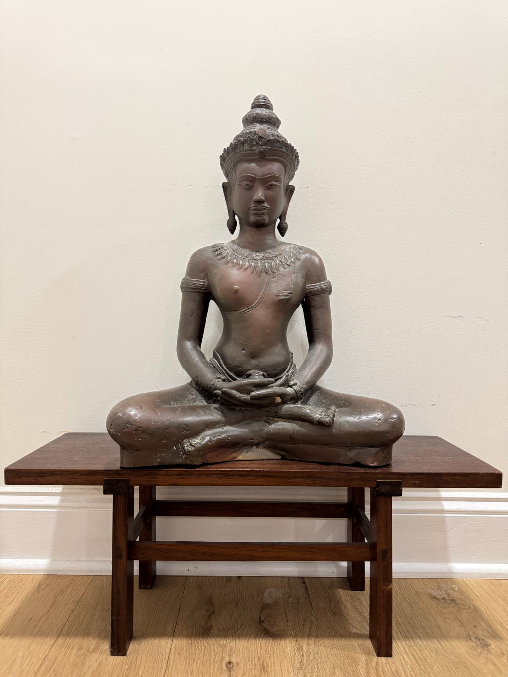 Another full-figure front view of the seated crowned Buddha in meditation pose on display table
