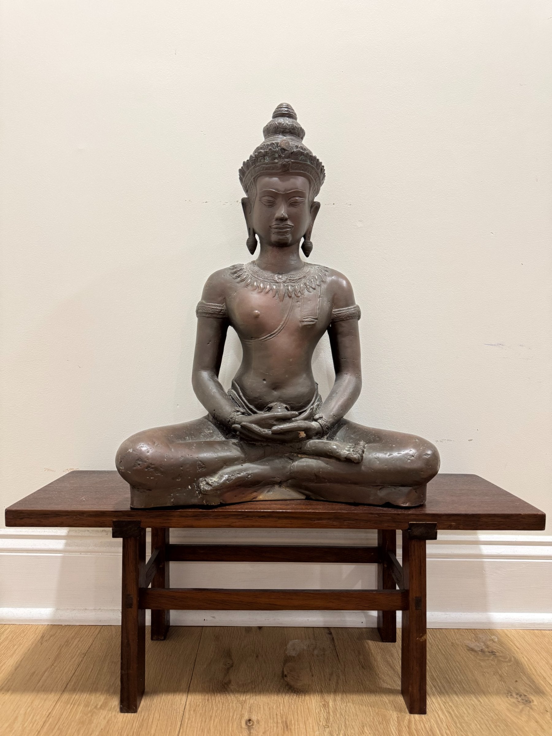 Another full-figure front view of the seated crowned Buddha in meditation pose on display table