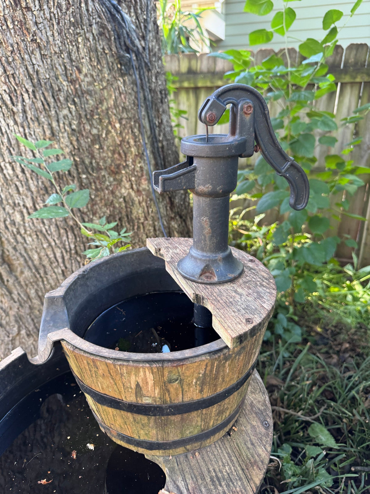Close-up of the cast-iron-look hand pump atop the wooden barrel tiers