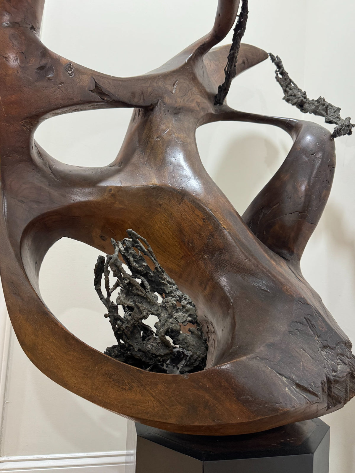 Full-length view of sculpture from front, tall organic abstract form with multiple circular negative spaces, rich brown wood grain visible