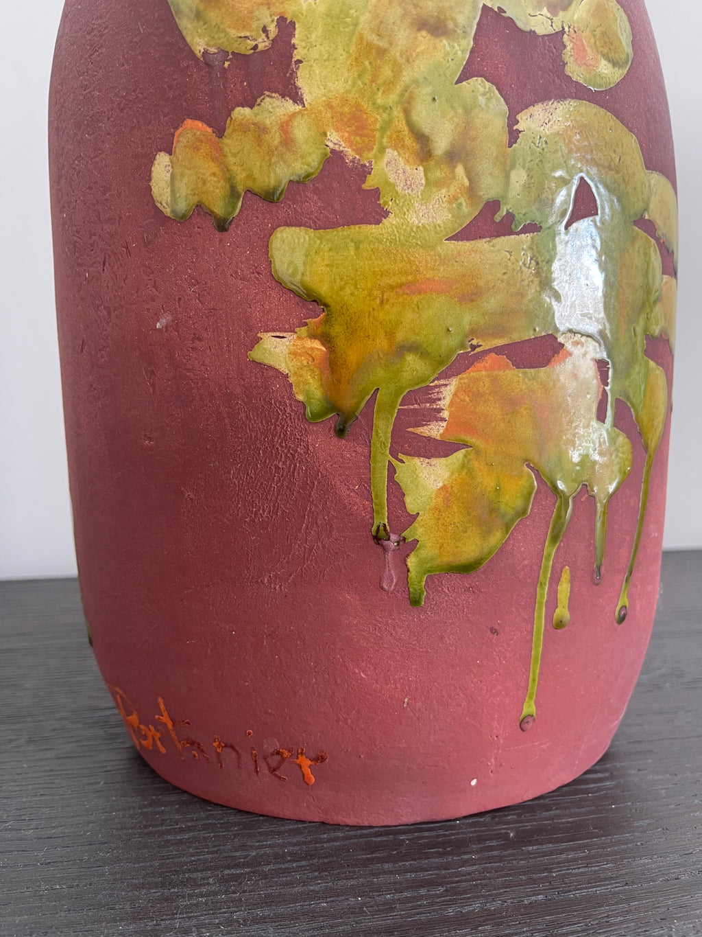Close-up of vase body showing yellow-green dripping glaze details over pink-red matte ceramic surface