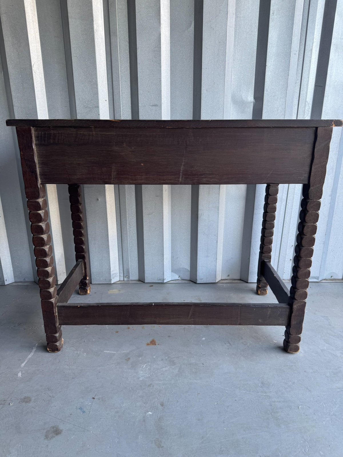 Rear view of desk showing dark wood construction, turned leg details, lower stretcher shelf