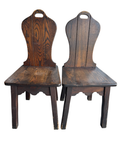 Pair of dark stained oak side chairs with curved backrests and handle cutouts, viewed from front
