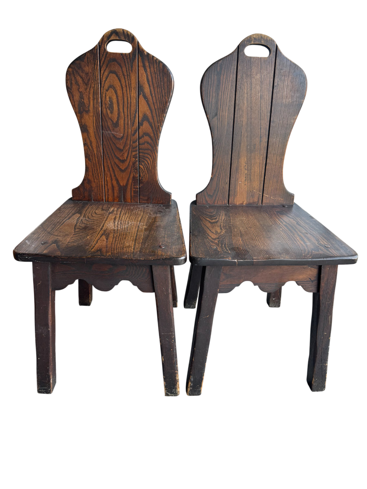 Pair of dark stained oak side chairs with curved backrests and handle cutouts, viewed from front