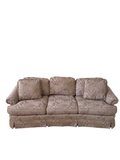 Mauve floral damask three-cushion sofa with rolled arms and skirted base, front view in room setting
