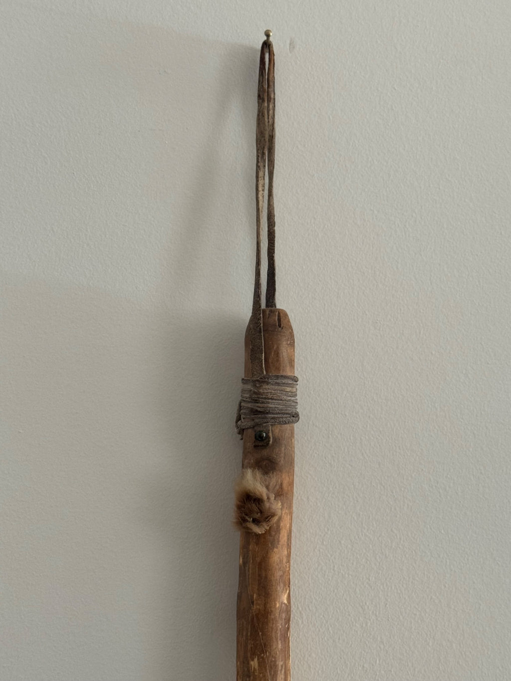 Detail of upper shaft showing wooden handle with rope binding and split prong tips at top of spinning tool