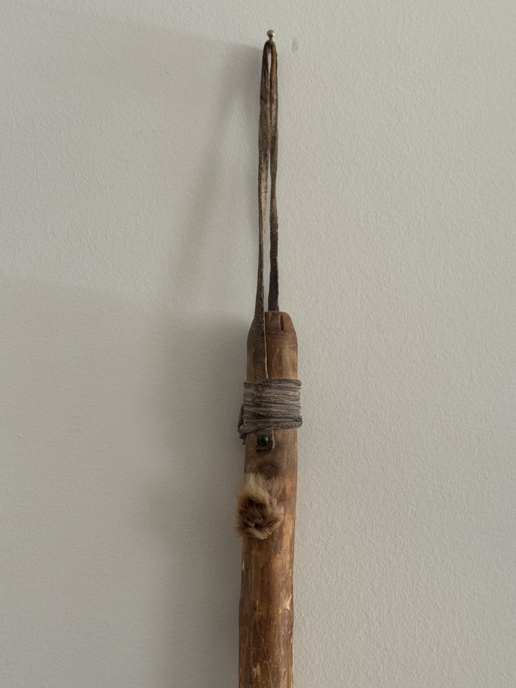 Detail of upper shaft showing wooden handle with rope binding and split prong tips at top of spinning tool