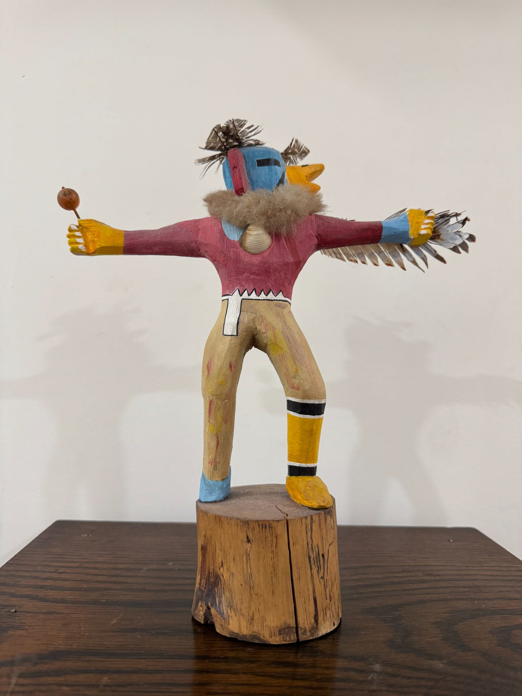 Complete kachina figure photographed against white background showing full carved form with extended arms and feathered details