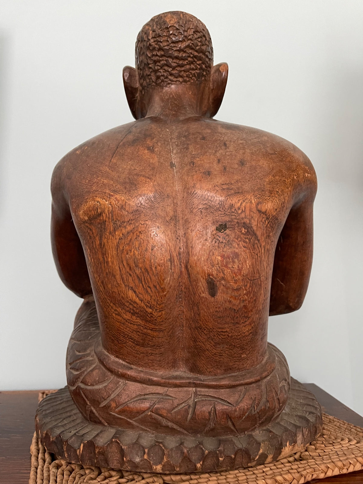 Rear view of bare back and shoulders with wood grain visible, seated position on woven base