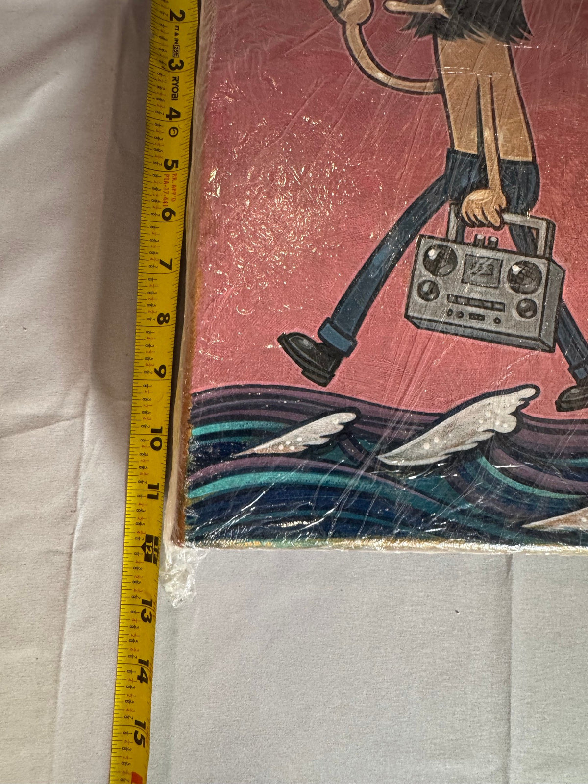 Tape measure held against the painting showing its size