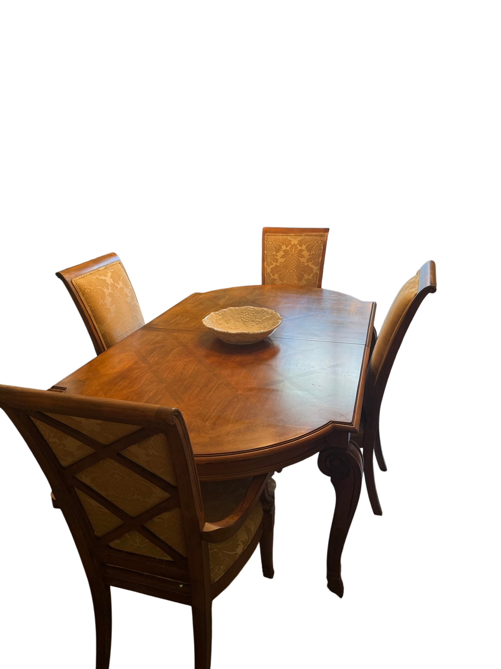 Formal dining room with wooden table, four upholstered chairs, ornate gold chandelier, floral wallpaper