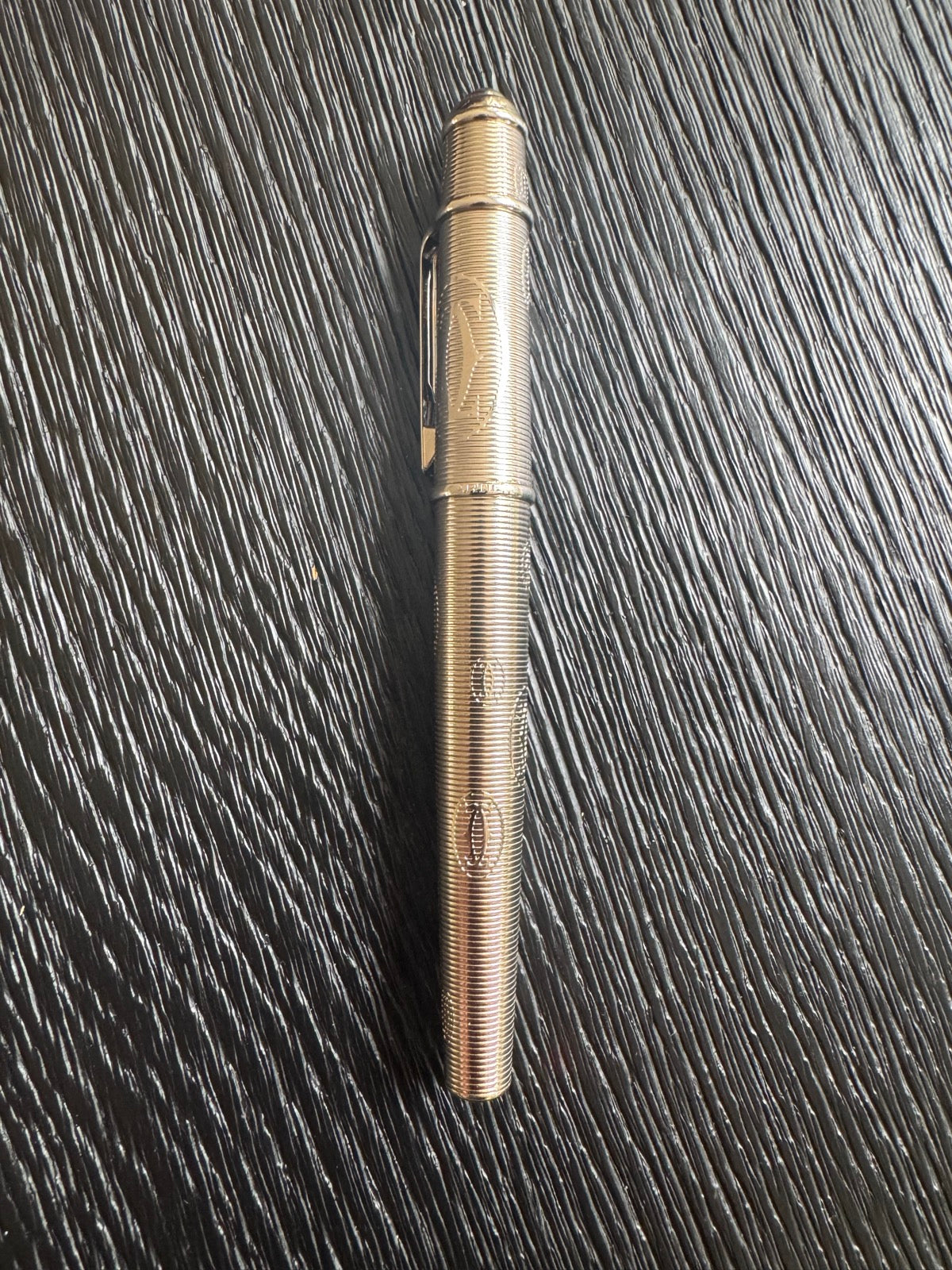 Full-length view of palladium-finish rollerball pen with spiral ribbed pattern and black grip section