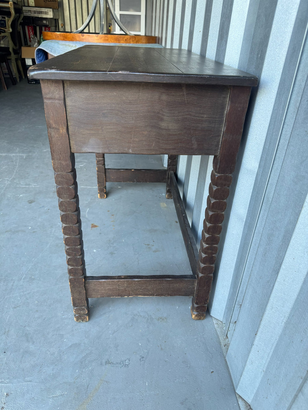 Side profile of desk revealing drawer depth, turned leg spindles, dark finish and metal hardware