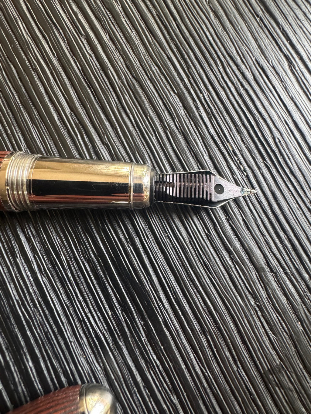 Wooden fountain pen with wood barrel, gold-plated trim band, and dark nib section, displayed horizontally