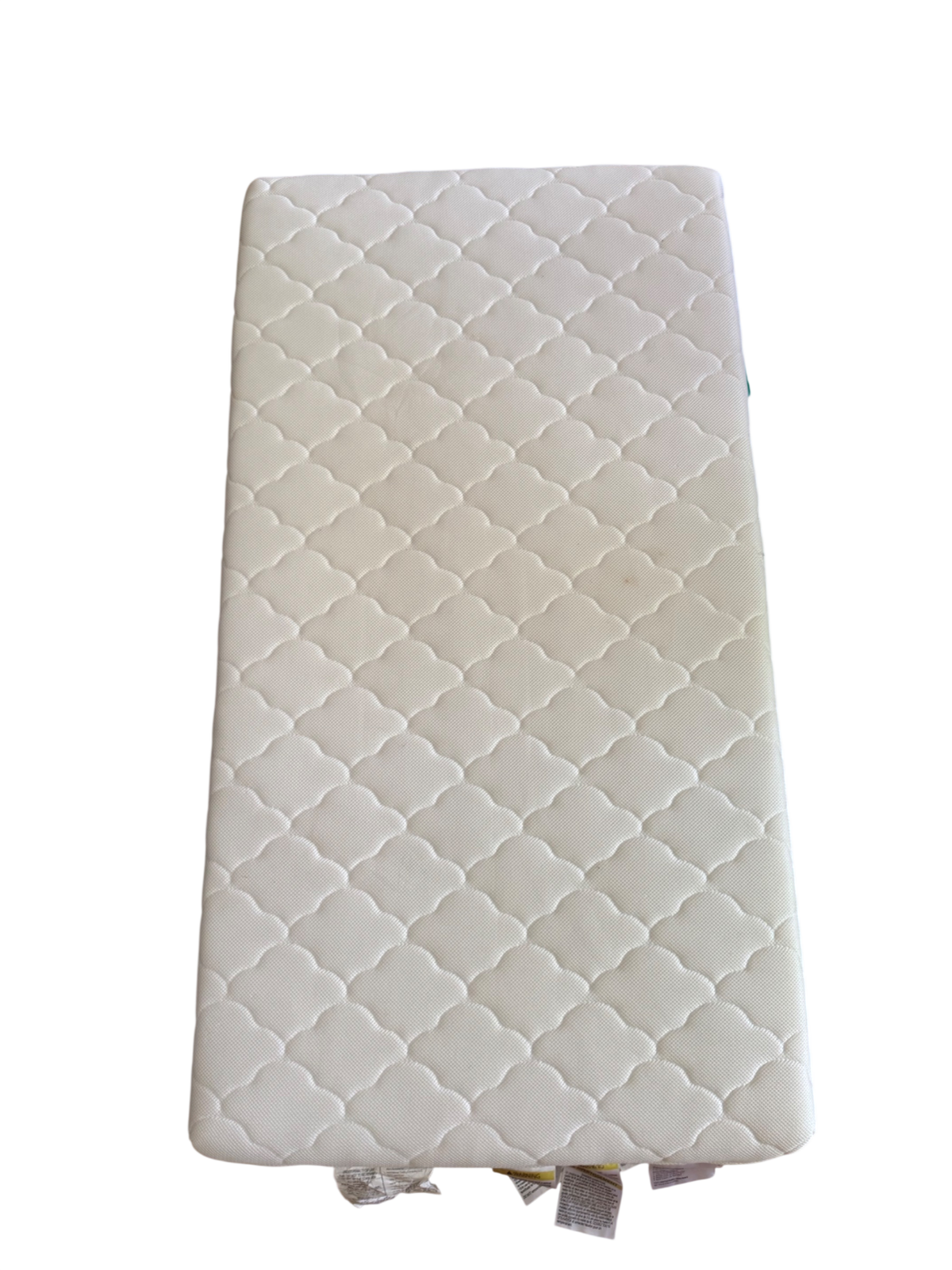 White quilted crib mattress with diamond quilting pattern, viewed from above at an angle