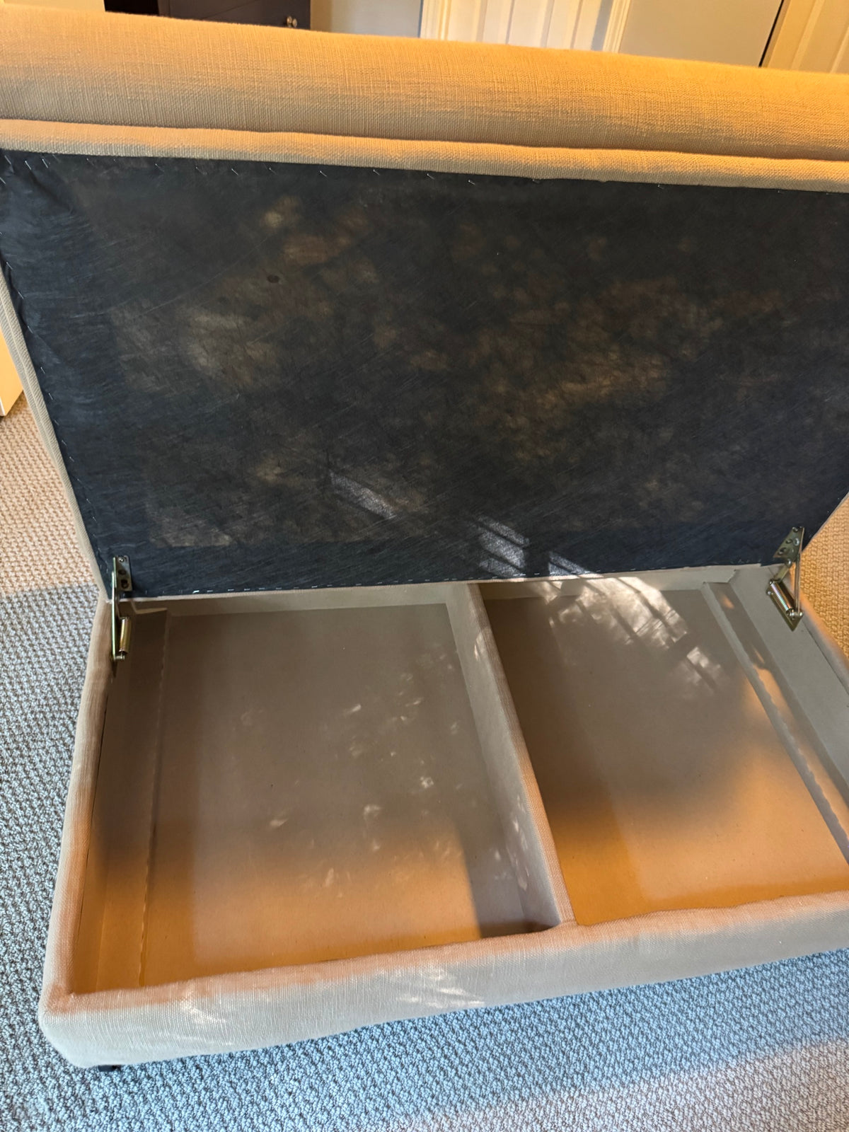 Interior view of tan storage ottoman showing open hinged lid and storage compartment