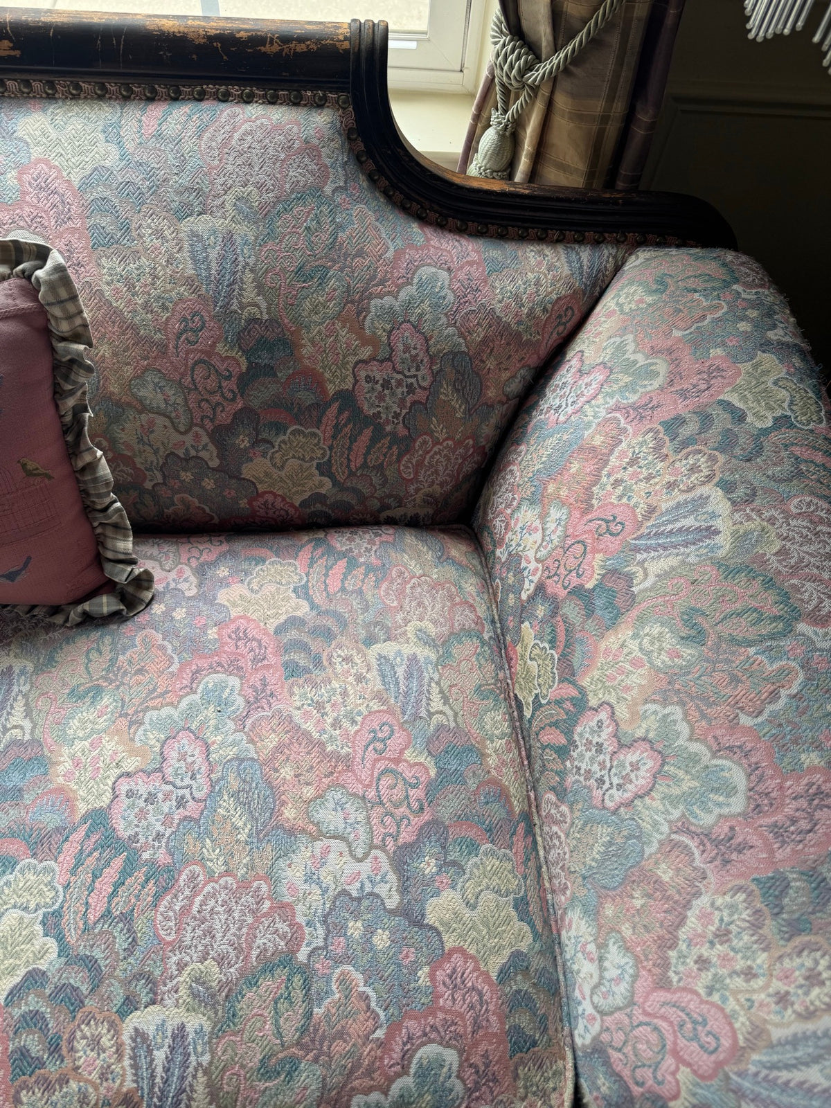 Seat and back detail of the carved sofa showing pastel floral tapestry upholstery and the carved crest rail