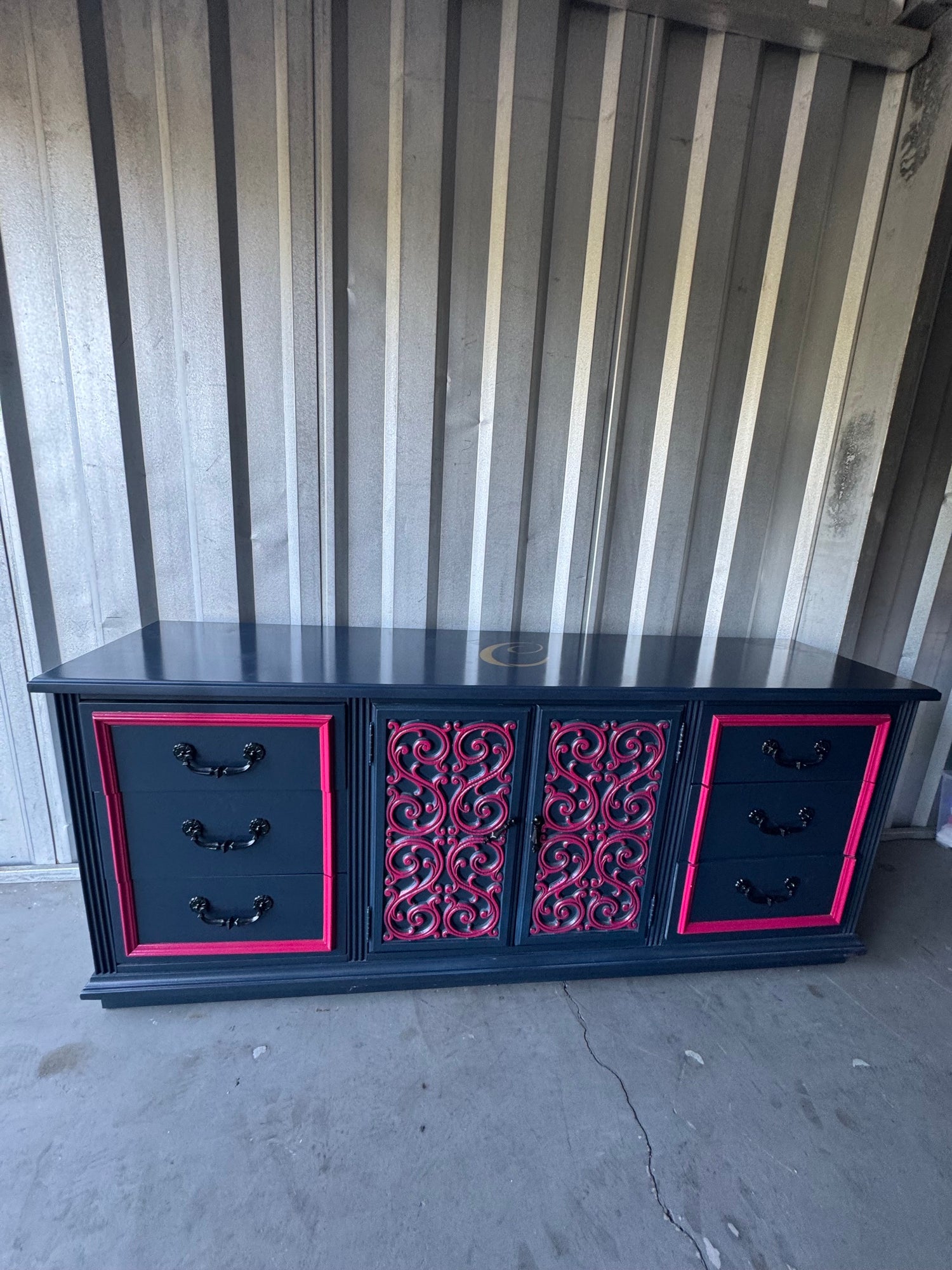Long navy credenza with pink trim, drawers on sides, decorative doors in center, full front view