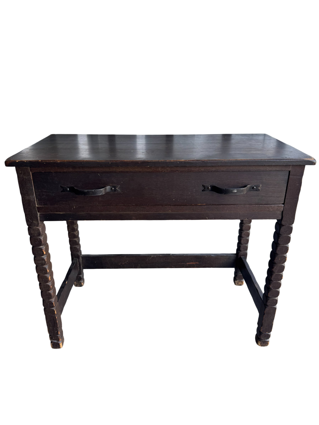 Front view of dark wood desk with two black metal handles, turned legs, lower shelf, angled perspective