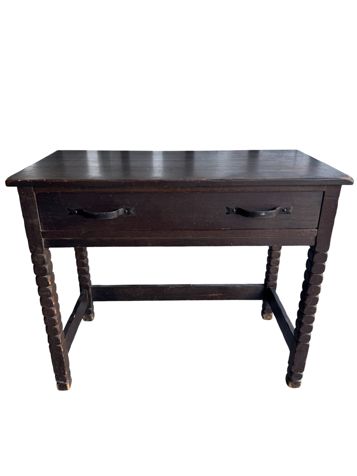 Front view of dark wood desk with two black metal handles, turned legs, lower shelf, angled perspective