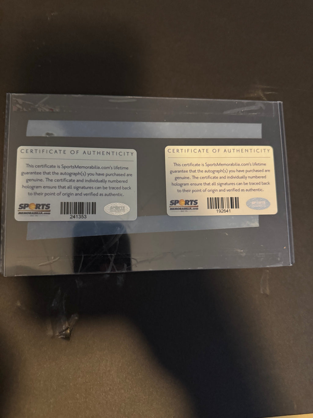 Back of display packaging showing two Sports Memorabilia.com certificate of authenticity stickers with hologram numbers
