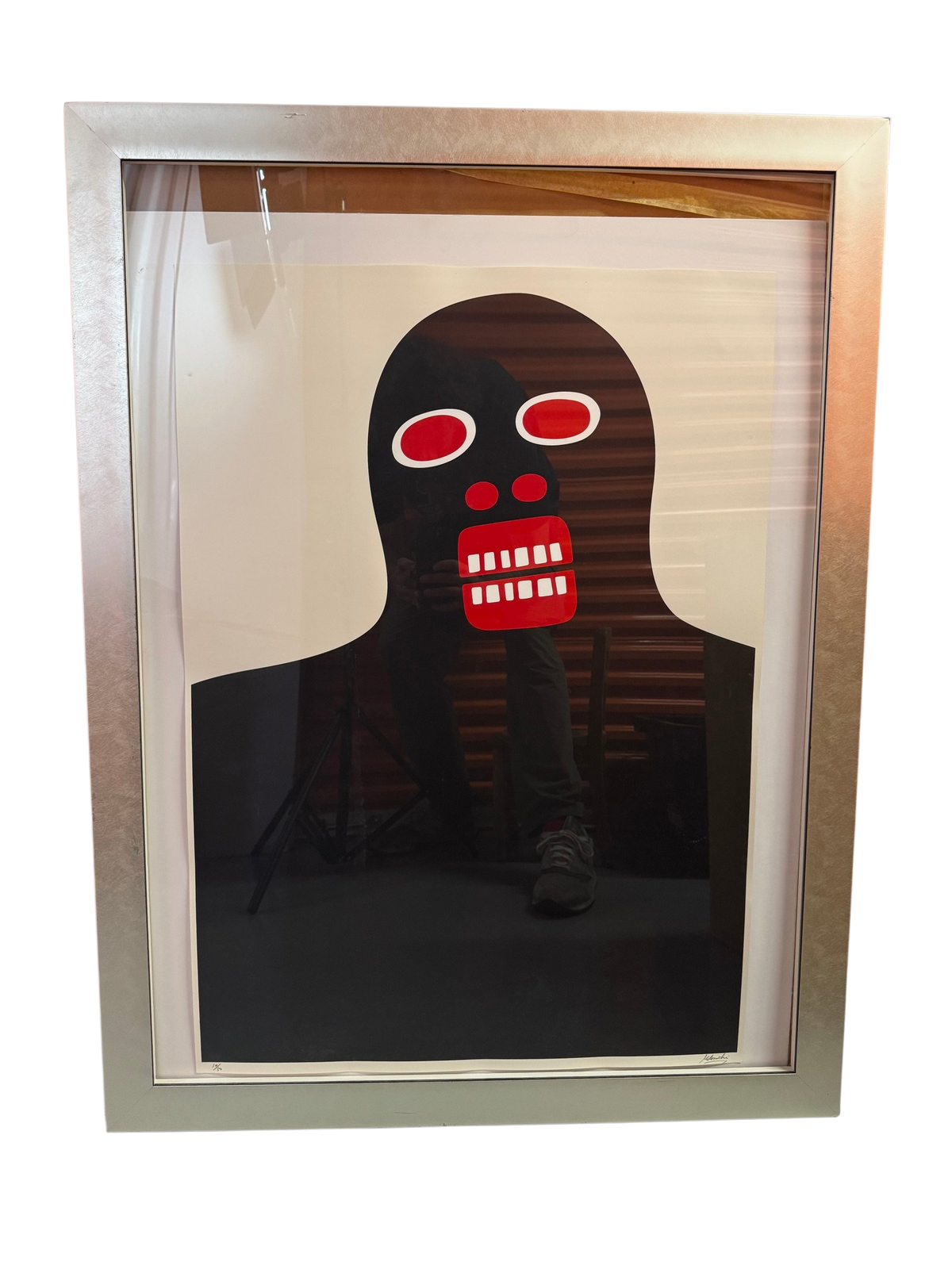 Black figure with red teeth print in silver frame, straight-on