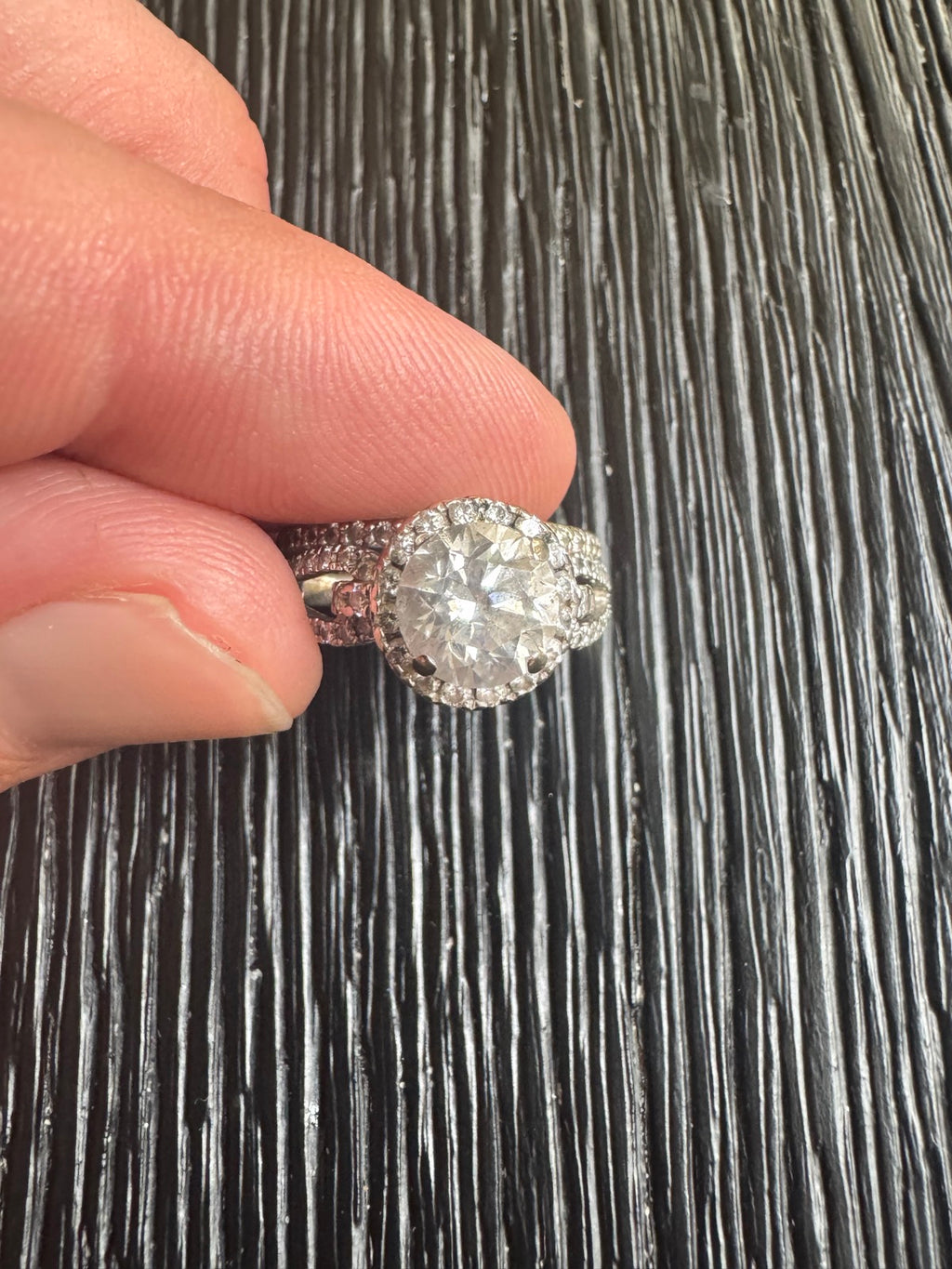 Close-up of diamond center stone and halo setting held in hand, showing sparkle and detail