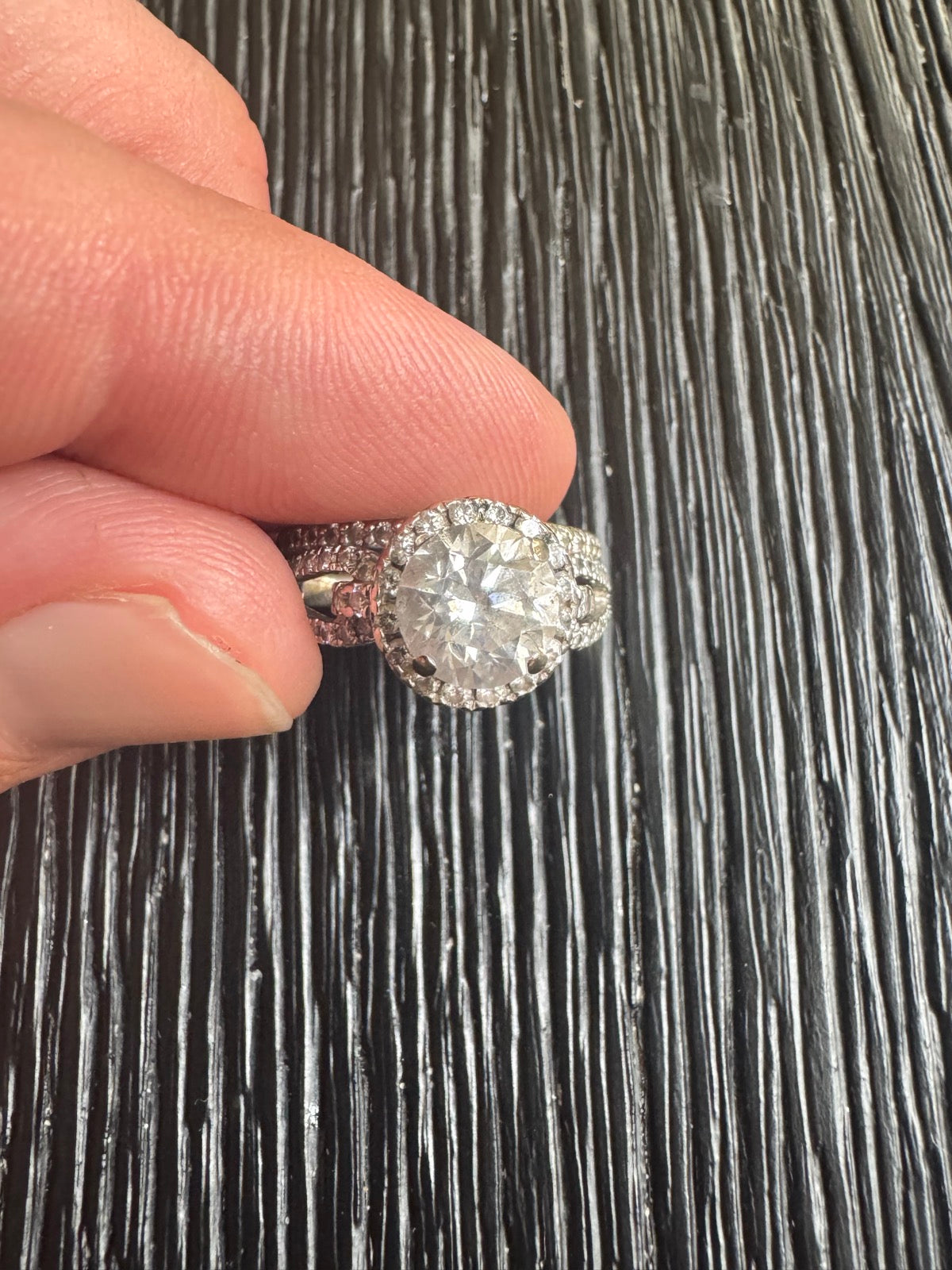 Close-up of diamond center stone and halo setting held in hand, showing sparkle and detail
