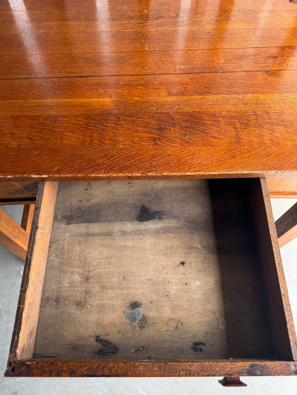 Tabletop surface closeup displaying wood grain, finish patina, and visible wear marks across the surface
