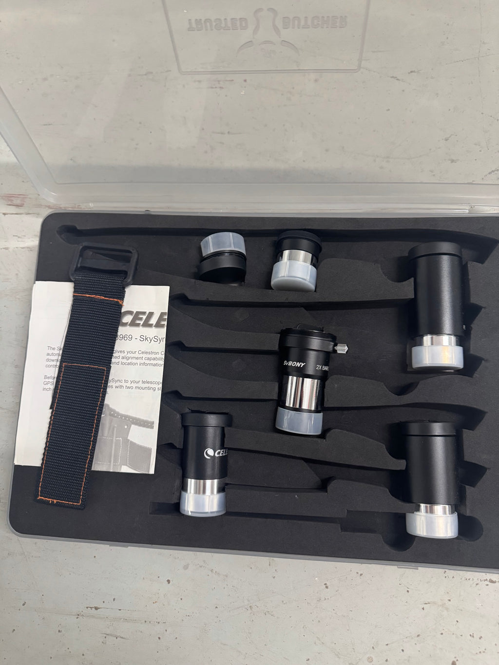 Open accessory case displaying eyepieces, barlow lens, strap and documentation materials