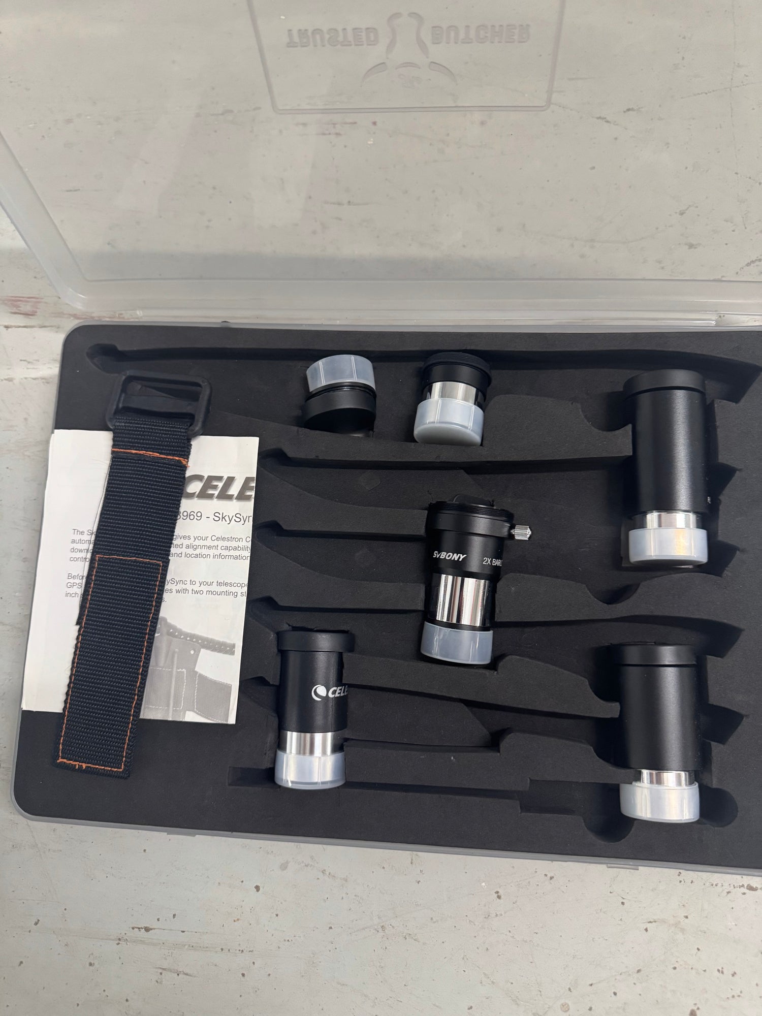 Open accessory case displaying eyepieces, barlow lens, strap and documentation materials