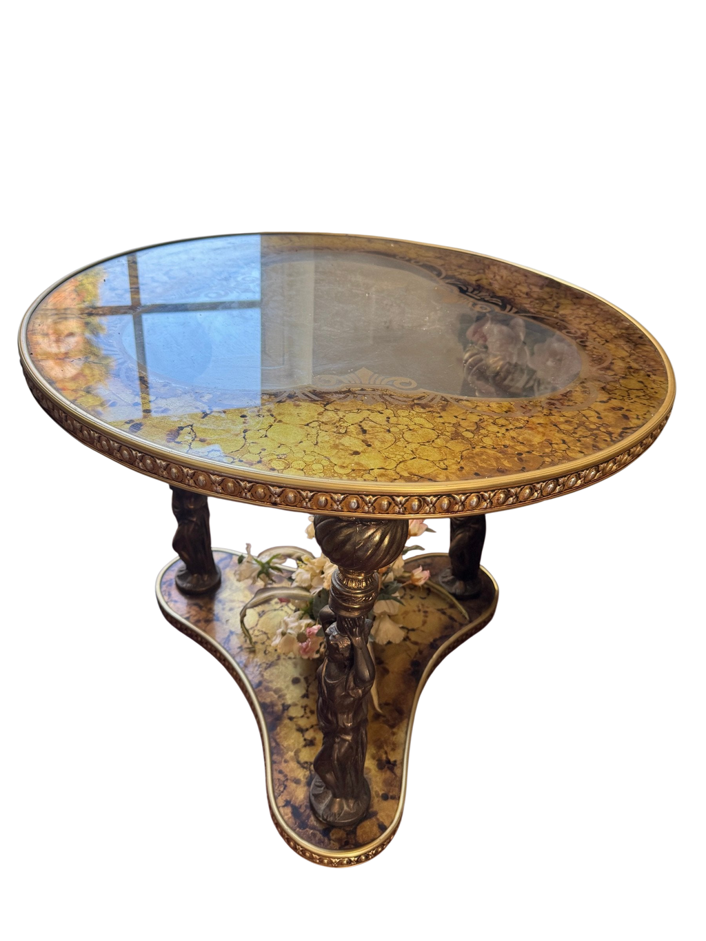 Gilt glass accent table with figural supports seen from the side