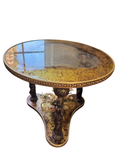 Gilt glass accent table with figural supports seen from the side