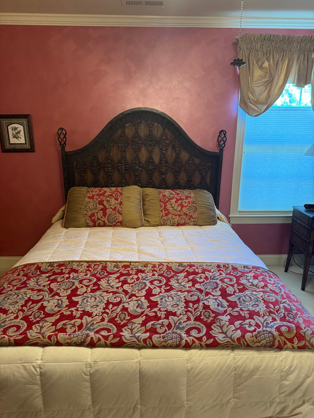 Queen bed with dark carved wooden headboard, cream quilted mattress, red and gold damask bedding, gold pillows in pink bedroom