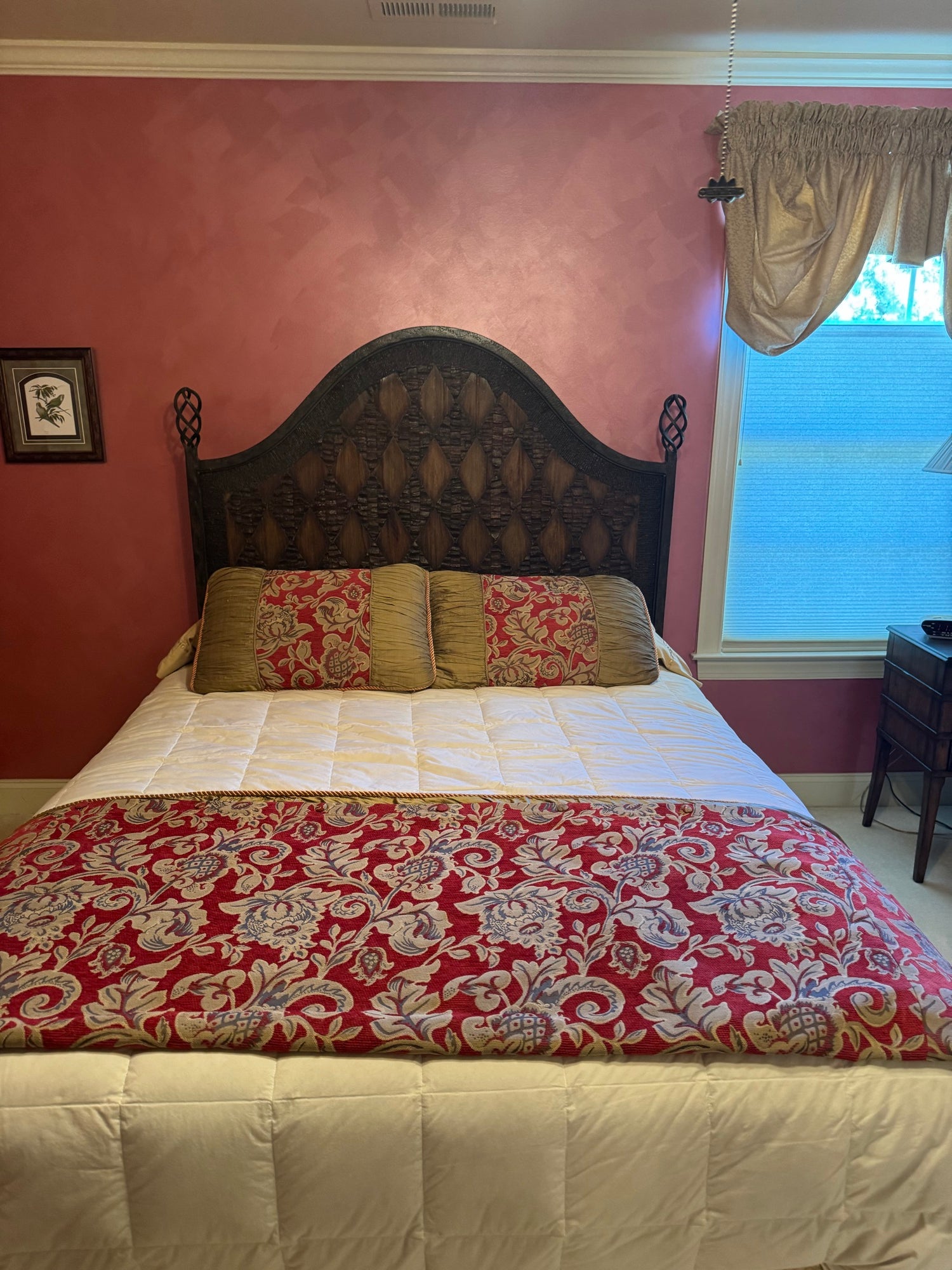 Queen bed with dark carved wooden headboard, cream quilted mattress, red and gold damask bedding, gold pillows in pink bedroom