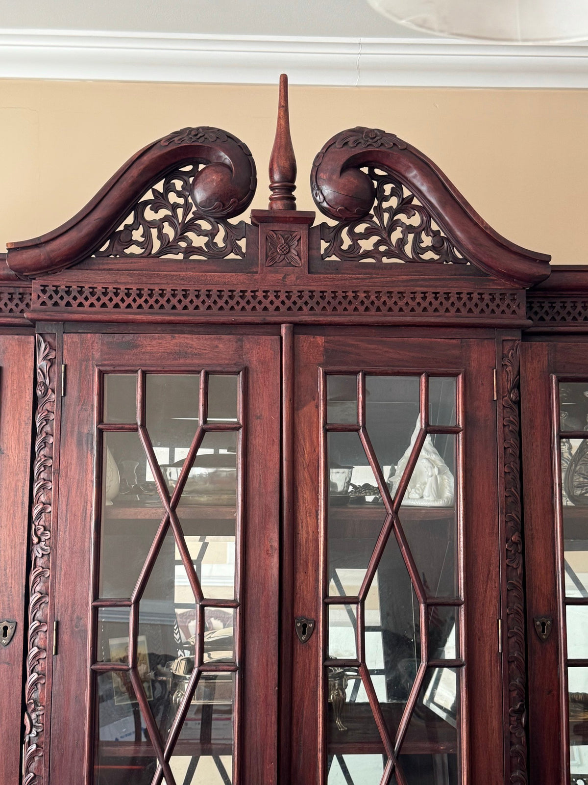 Carved pediment and lattice-glass doors at the top of the cabinet