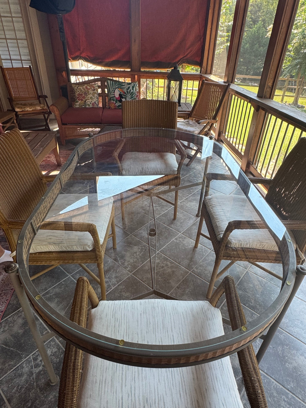 Overhead view of complete dining set showing oval glass table and five wicker armchairs arranged around it